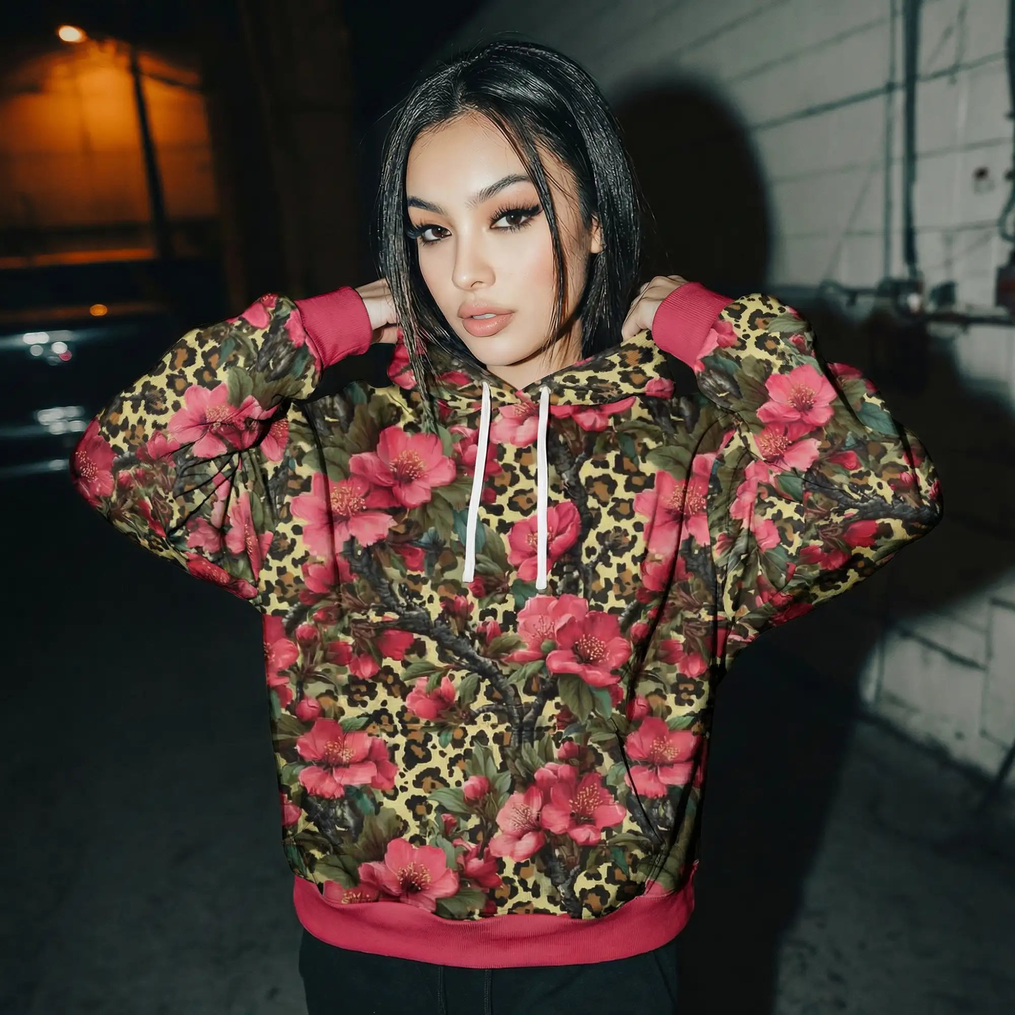 A vibrant leopard print hoodie adorned with bold pink floral patterns and accented with magenta ribbed cuffs, waistband, and drawstrings.
